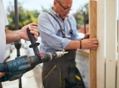 A handyman in Hampstead, NC, uses a drill to construct a wooden fence, showcasing his skills in home improvement.