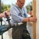 A handyman in Hampstead, NC, uses a drill to construct a wooden fence, showcasing his skills in home improvement.